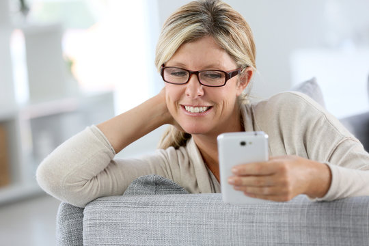 Cheerful woman reading text message on phone