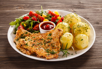 Fried pork chop, boiled potatoes and vegetable salad