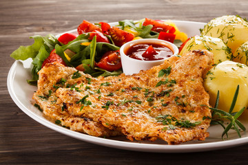 Fried pork chop, boiled potatoes and vegetable salad
