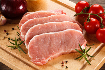 Raw pork chops on cutting board and vegetables