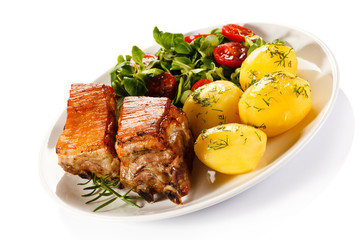 Tasty grilled ribs with vegetables on white background