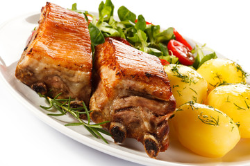 Tasty grilled ribs with vegetables on white background