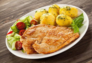 Fried pork chop, boiled potatoes and vegetable salad