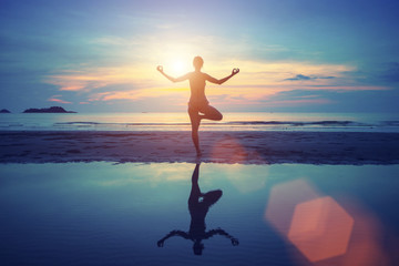 Young yoga woman meditation on the beach at sunset.