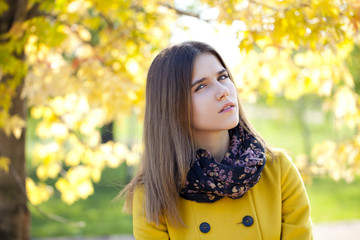 Naklejka premium Happy young woman in yellow coat in autumn street
