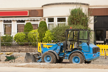 Fototapeta na wymiar Strassenbauarbeiten mit einem blauen Baggerlader