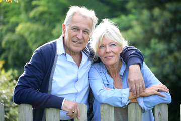 Senior couple standing by fence in yard