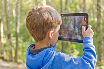 child in the woods with the tablet pc