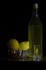 Limoncello con limoni su sfondo nero