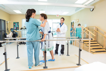 Physical Therapist Assisting Patient In Walking - obrazy, fototapety, plakaty