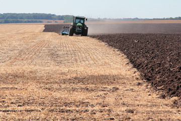 Fototapeta premium Tractor plows the land