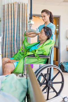 Nurse Removing Straps From Hydraulic Lift With Patient On Wheelc
