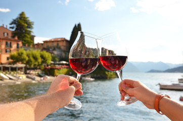 Two wineglasses in the hands. Varenna town at the lake Como, Ita