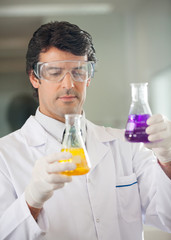 Scientist Examining Flasks With Different Chemicals