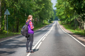 Beautiful girl with backpack walking on the road