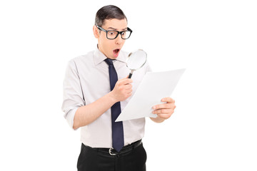 Shocked man looking at document through magnifier