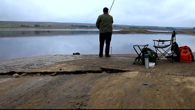 man fishing at reservoir uk