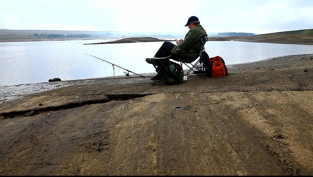 man fishing at reservoir uk