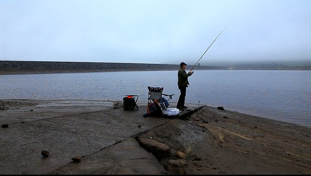 man fishing at reservoir uk