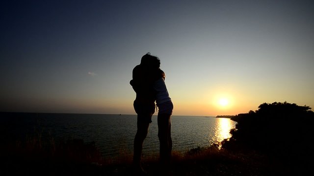 Couple hugging ad kissing at sunset on the beach