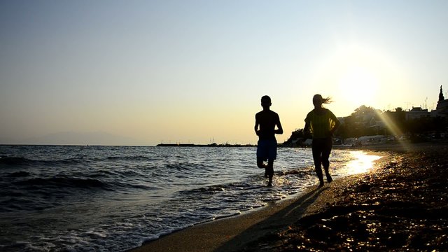 Couple jogging on the beach at sunset