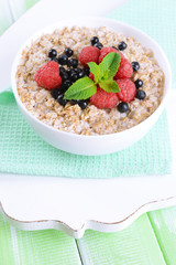 Tasty oatmeal with berries on table close-up