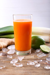 Glass of fresh carrot juice and vegetables on wooden table