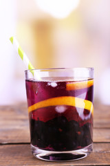 Glass of cold berry cocktail with lemon on wooden table