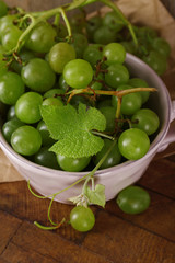Green grapes in bowl on wooden background