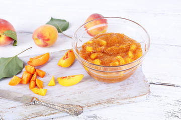 tasty peach jam with fresh peaches on wooden table