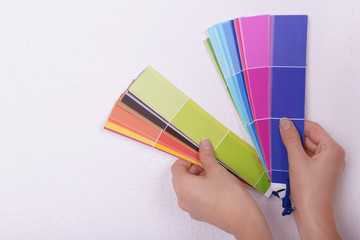 Woman choosing color for wall from swatches in room