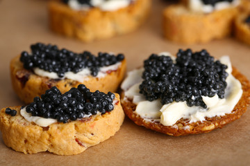 Slices of bread with butter and black caviar on paper