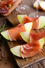 Delicious melon with prosciutto on table close-up