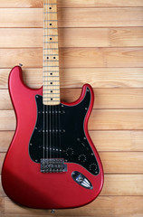 Naklejka na ściany i meble Red guitar on wooden background