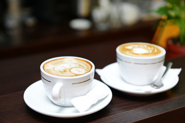 Cups of coffee with cute drawing in cafe