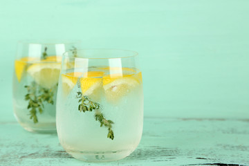 Tasty cool beverage with lemon and thyme, on wooden background