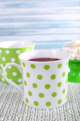 Two cups and sugar on white tablecloth on light background