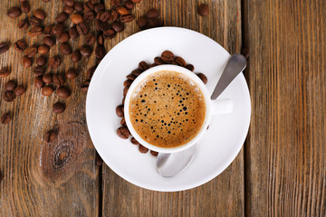 Cup of coffee with milk and coffee beans on wooden background