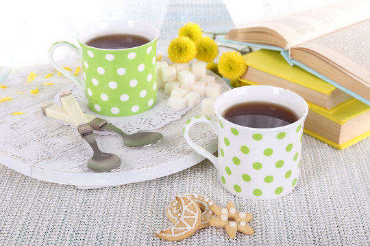 Two cups of tea with biscuits and books