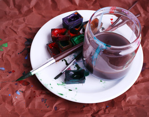 Watercolor paint cubes with brushes and jar with water