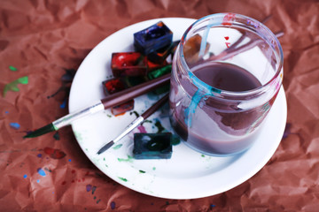 Watercolor paint cubes with brush and jar with water