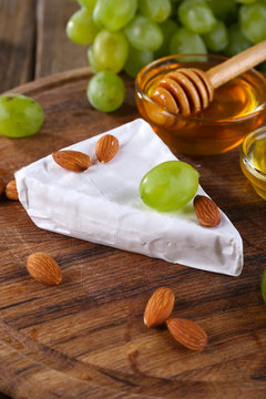 Brie cheese, honey in glass bowl, nuts and grapes