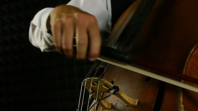 Cellist playing on cello. Detail shot on musical instrument.