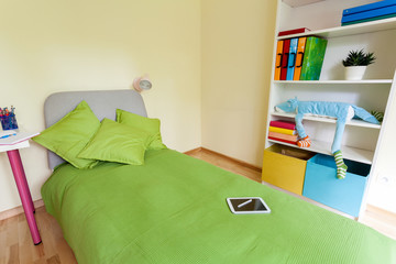 Digital tablet on bed in children bedroom