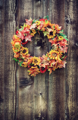 Weathered autumn flower wreath against wooden background