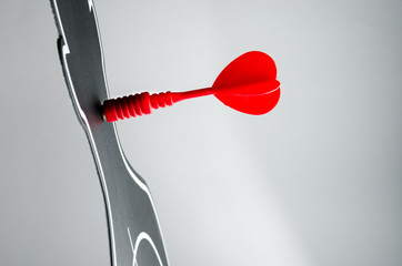 red arrow at dart board in profile shape on grey background