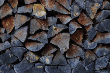 Background of dry chopped firewood logs in a pile  at the wall