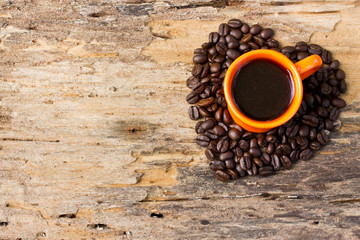 Cup of black coffee and Coffee beans arranged in heart shape on