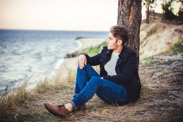 Naklejka na ściany i meble young man on sea background. autumn beach