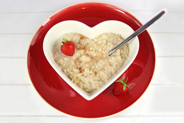 Breakfast of Oatmeal or Proodge in a heart bowl wit hstrawberry
